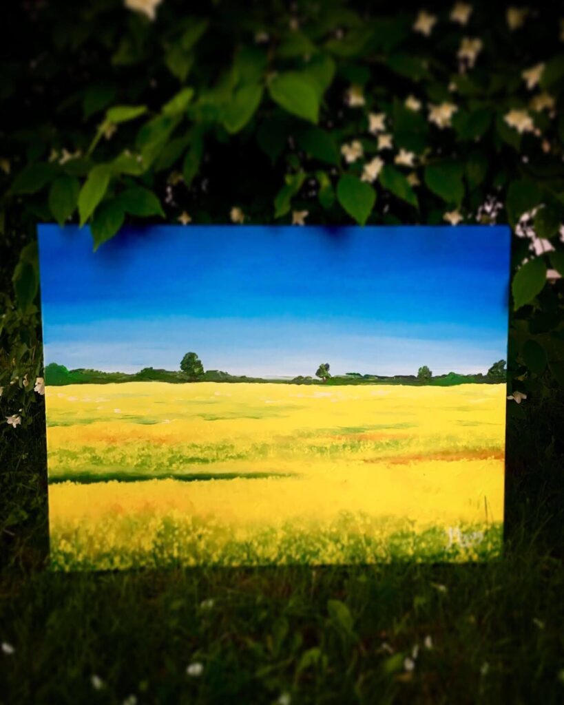 Landscape painting of a bright yellow field under a deep blue sky, with green trees in the distance. The scene captures the warmth and calm of a summer day.