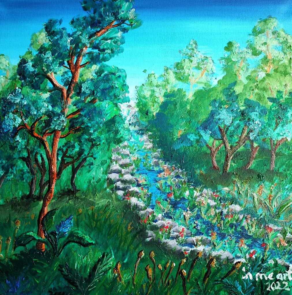 A vibrant forest scene painted in rich greens and blues, depicting a lush woodland with tall trees, thick grass, and wild plants. A rocky stream flows diagonally from the background to the foreground, with sparkling blue water and scattered colorful flowers along its path. The sunlight filters through the dense foliage, creating a serene, magical atmosphere. The artist’s signature 'in me art 2023' is visible in the bottom right corner.